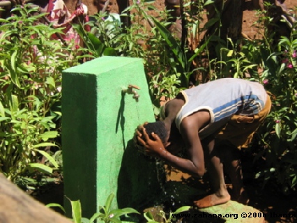 boy washing hair at water faucet in Madagascar